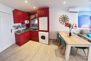 eine Küche mit roten Schränken, einem Tisch und einem Esszimmer in der Unterkunft Zenmarina 614 playa carihuela in Torremolinos