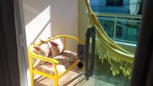 una silla amarilla en un balcón con hamaca en Casa da Celia, en Arraial do Cabo