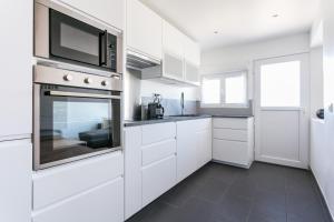 a kitchen with white cabinets and a microwave at Luxury Penthouse in Naturiste; FKK, Nudist Village in Cap d'Agde