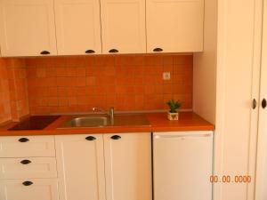 a kitchen with white cabinets and a sink at Villa Kostandin in Qeparo