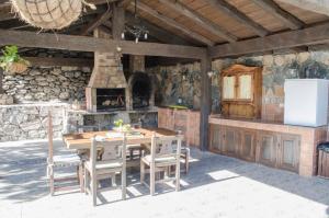 Una cocina al aire libre con una mesa y sillas de madera. en Vivelorural casa en Valle de Chira con piscina, en San Bartolomé