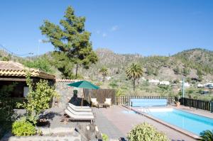 Una piscina con sillas y una sombrilla al lado de una casa. en Vivelorural casa en Valle de Chira con piscina, en San Bartolomé