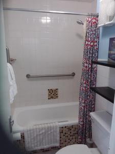 a bathroom with a tub and a toilet and a shower curtain at McFarlane's Place in Ocho Rios