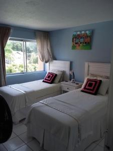a bedroom with two beds and a window at McFarlane's Place in Ocho Rios