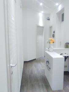 a white bathroom with a vase of flowers on a counter at B&B del Centro in Capo dʼOrlando
