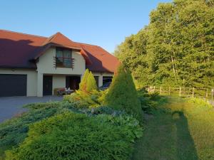 a house with trees in front of a yard at Roguļi in Cērkste
