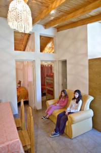 2 femmes assises sur un canapé dans un salon dans l'établissement Cabañas Orión, à Potrerillos