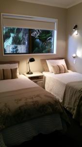 two beds in a bedroom with a large window at Mooring Lane Lodge in Whitianga