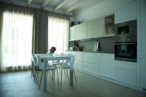 una cucina con tavolo, mobili bianchi, tavolo e sedie di Sirmione Park View Luxury Apartments a Sirmione
