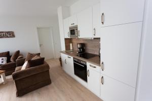 a kitchen with white cabinets and a living room at Komfort-Ferienwohnung Waterkant by Meer-Ferienwohnungen in Olpenitz