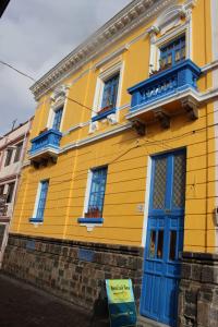 un edificio amarillo con puertas y ventanas azules en Hostal Café Tiana, en Latacunga