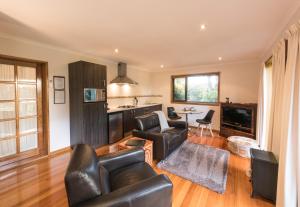 a living room with leather furniture and a kitchen at Parnella Kettering in Kettering