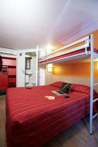 a bedroom with a red bed with a laptop on it at Premiere Classe Beziers in Béziers
