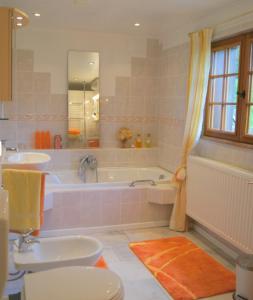 La salle de bains est pourvue d'une baignoire, de toilettes et d'un lavabo. dans l'établissement Chambres d'hotes Le Haut de la Tuilerie, à Fresnay-le-Samson