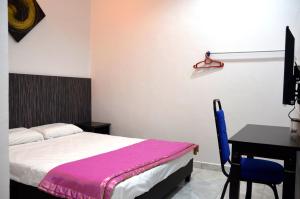 a bedroom with a bed and a table and a desk at Homestay Klebang Ipoh in Ipoh