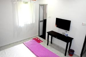 a living room with a table and a tv and a pink rug at Homestay Klebang Ipoh in Ipoh