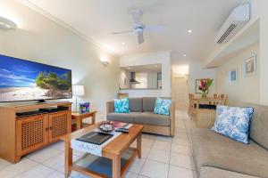 a living room with a couch and a tv at Mowbray By The Sea in Port Douglas