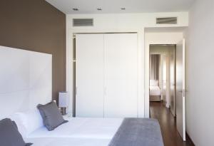 a bedroom with a large white bed and a bathroom at MH Apartments Suites in Barcelona