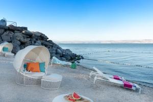 uma praia com cadeiras e uma tenda e a água em U Boutique Kinneret by the Sea of Galilee em Tiberias