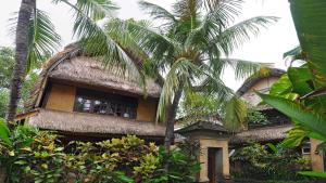 a building with a palm tree in front of it at Puri Dewa Bharata Hotel & Villas in Legian