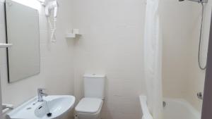 a white bathroom with a toilet and a sink at Hotel Montemar in Noja +49 photos