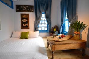a bedroom with a bed and a table and windows at Chikan West House in Tainan