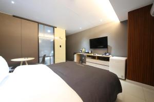 ein Hotelzimmer mit einem Bett und einem Flachbild-TV in der Unterkunft Hotel K in Jeonju