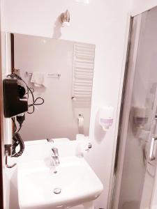 y baño blanco con lavabo y ducha. en Hotel i Restauracja Pod Skałą Jasło en Jasło