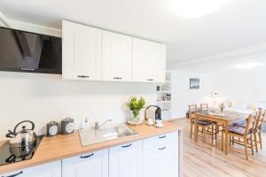 a kitchen with white cabinets and a table with a sink at Apartament Salmopolska5 in Szczyrk