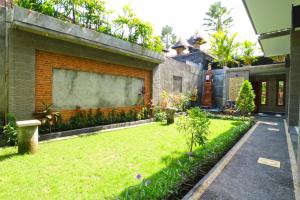 podwórko z zielonym trawnikiem obok budynku w obiekcie Gempita House Bali w mieście Legian