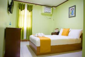 a bedroom with a bed in a room with a window at Royal Mansion Hotel in Tabaco