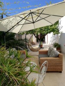 un patio con sofá y sombrilla en Agorà Suites & Apartments, en Manduria