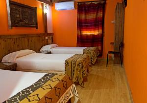 three beds in a room with orange walls at Hotel Plaza in Cuenca