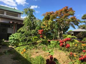 a garden with red flowers and plants in front of a house at Masugataya Ryokan in Tako