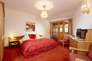 Dormitorio con cama, escritorio y TV en Hotel Kroneck, en Kirchberg in Tirol