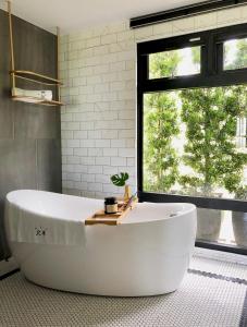 a large white tub in a bathroom with a window at Hotel Everyday Life in Eluan