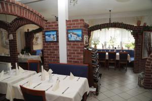 a dining room with white tables and a brick wall at Hotel Mykonos in Eschweiler