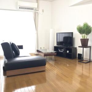 a living room with a black leather chair and a tv at PEARL KAMINOBORI F Plus in Hiroshima