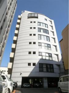 a tall white building with cars parked in front of it at PEARL KAMINOBORI F Plus in Hiroshima