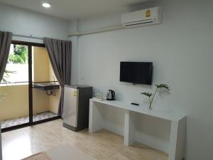 een woonkamer met een bureau, een tv en een tafel bij Prukpibul Apartment in Bangkok