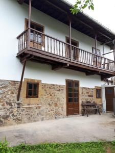 a house with a balcony and a picnic table at Casa Justa in San Martín de Luiña