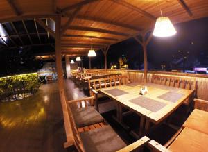 アナパにあるGuest House Equatorの木製のテーブルと椅子、照明が備わるレストラン