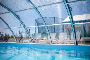 a swimming pool with chairs in a glass building at Wisełka Domki Letniskowe NEMO in Wisełka