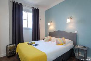 una camera da letto con un grande letto con una coperta gialla di Le Thimothée : Hôtel & Studios a Saint-Raphaël