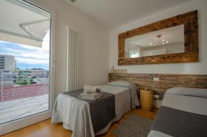 two beds in a room with a mirror and a balcony at Soleis Sea View Spa Apartment in Lignano Sabbiadoro