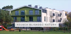 a large building with a sign in front of it at Apartamenty Pod Żaglami in Dziwnówek