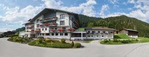 ein großes weißes Gebäude mit Blumen auf einem Parkplatz in der Unterkunft Hotel Sonnschupfer in Schladming