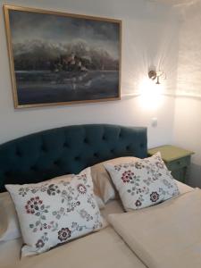 a bed with two pillows and a painting on the wall at Pletna Lake View Apartment (Ground Floor) in Bled