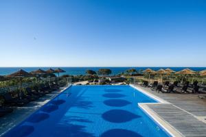 a swimming pool with chairs and the ocean in the background at Vila Alba Resort in Carvoeiro