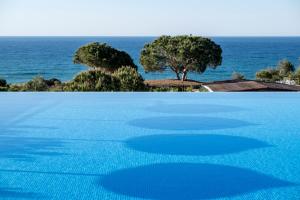 a swimming pool with the ocean in the background at Vila Alba Resort in Carvoeiro